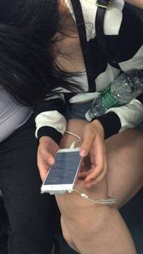 地铁上只顾着低头玩手机的女孩