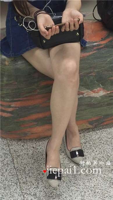 尖嘴高跟齐逼牛仔短裙妹子坐在玉石上看手机视频。