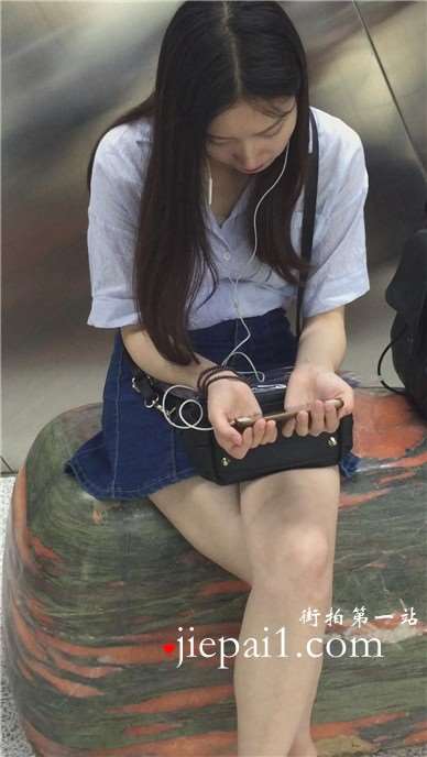 尖嘴高跟齐逼牛仔短裙妹子坐在玉石上看手机视频。