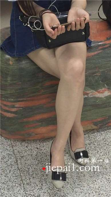 尖嘴高跟齐逼牛仔短裙妹子坐在玉石上看手机视频。
