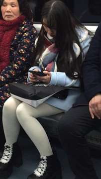 低头玩手机的白丝袜美腿可爱萌妹子。
