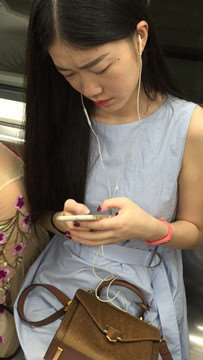 地铁拍摄低头玩手机的小清新美女