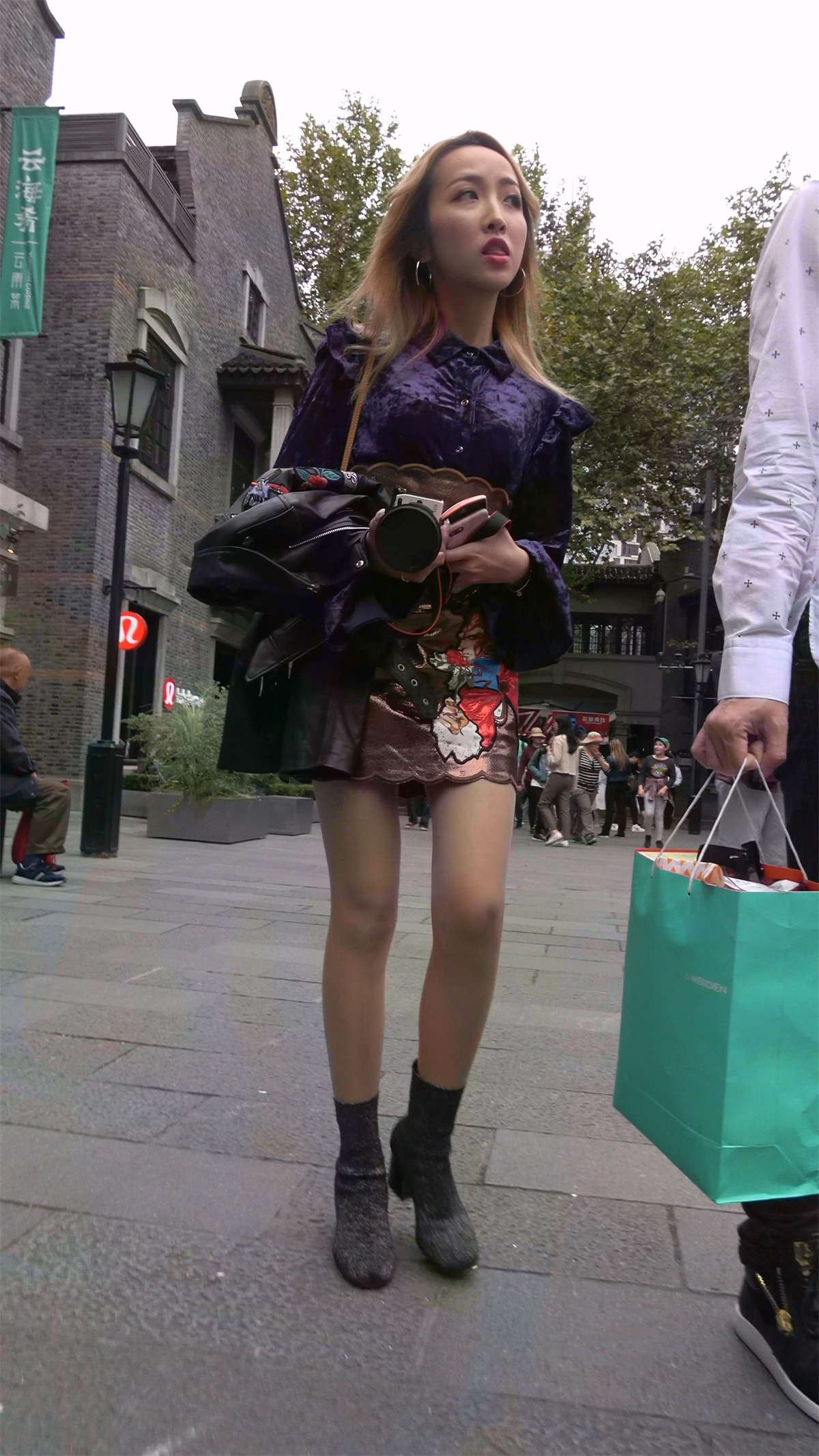 手持单反的时尚美裙美腿姑娘