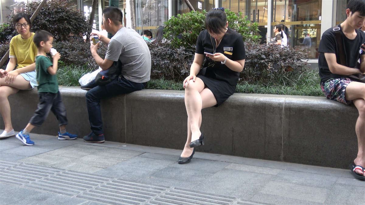 花圃边玩手机的制服街拍美女