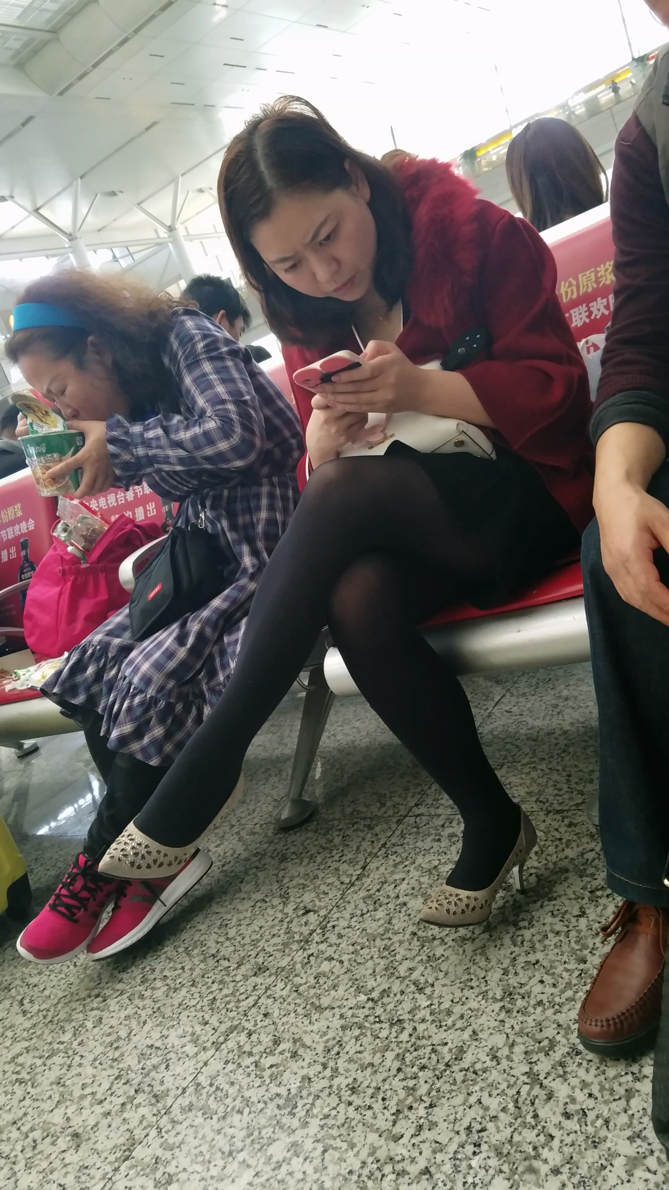 高铁站候车大厅等车的黑色丝袜美腿少妇