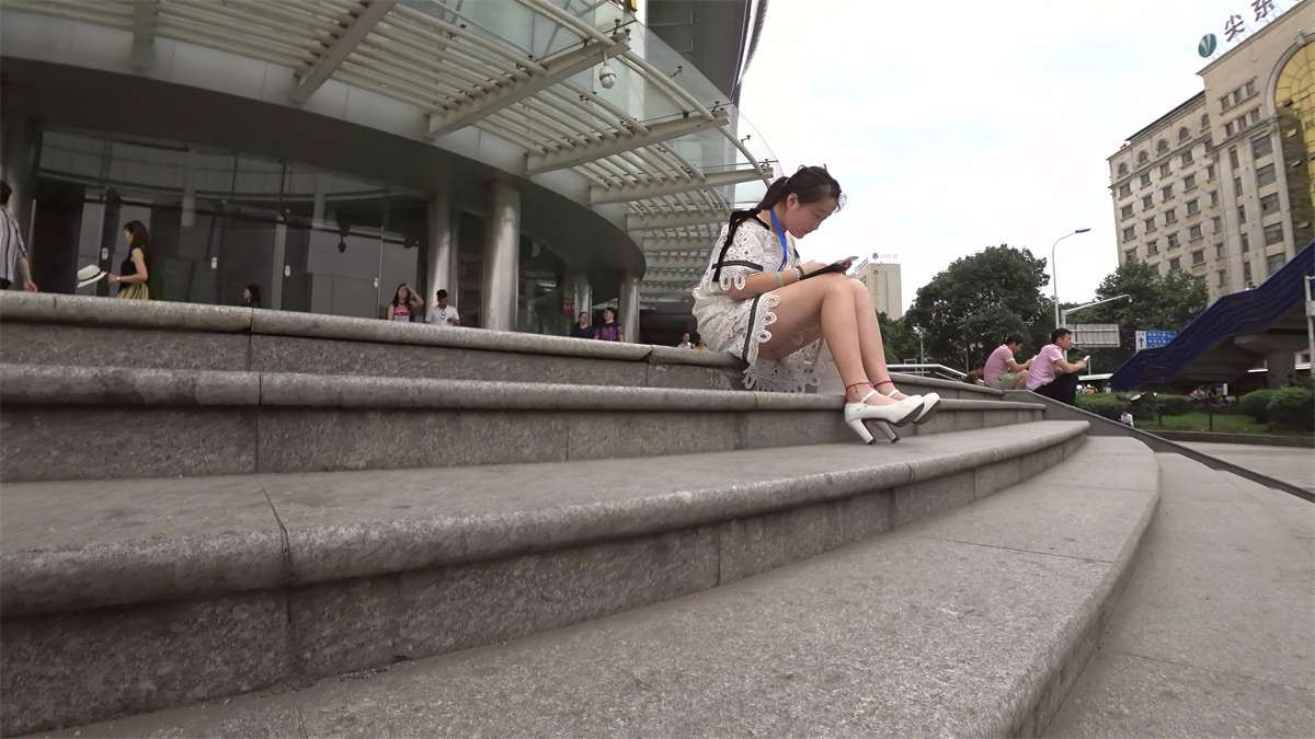 街拍专心玩手机的白色高跟白色蕾丝连衣短裙美眉