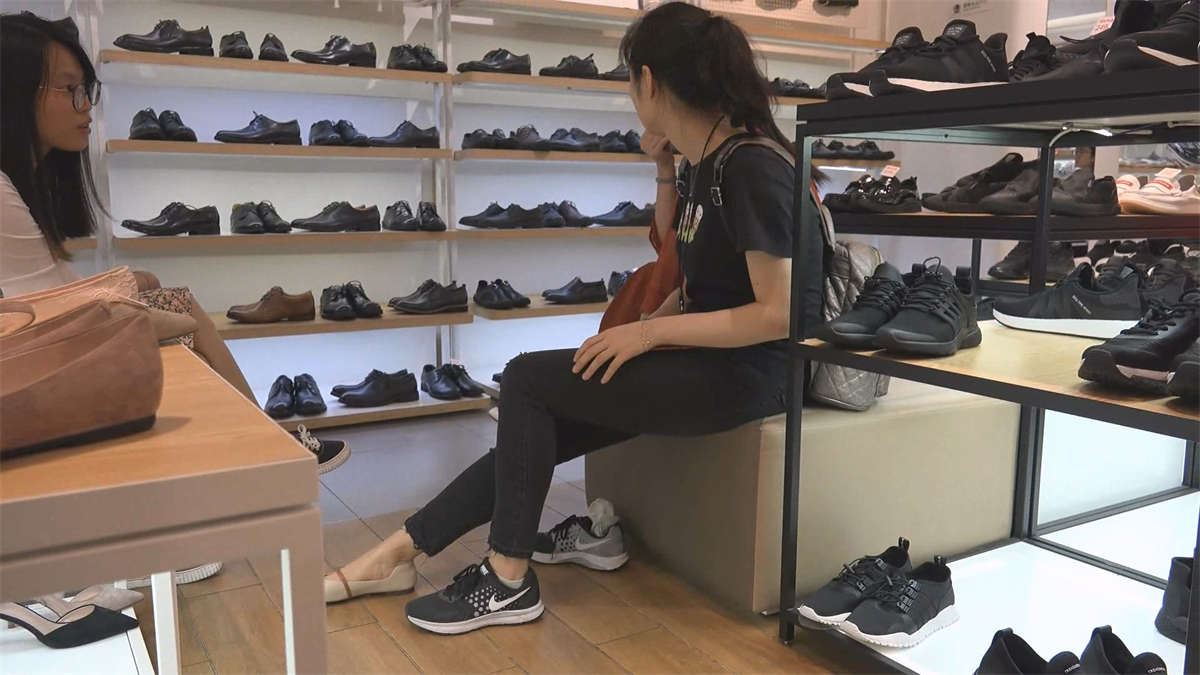 妈妈带着女儿来商场试穿鞋试完鞋后穿上白色袜子