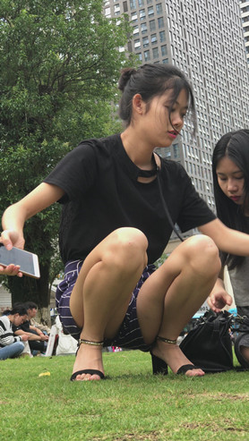 草地上玩手机的漂亮小姐姐