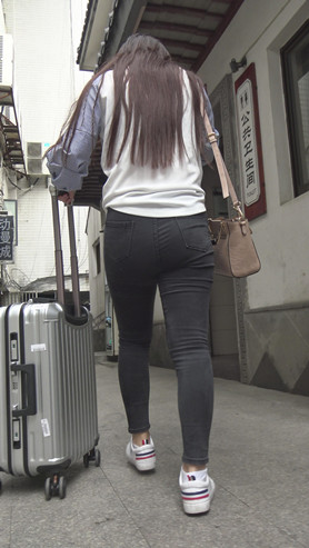 推着行李箱的黑色紧身牛仔裤女孩