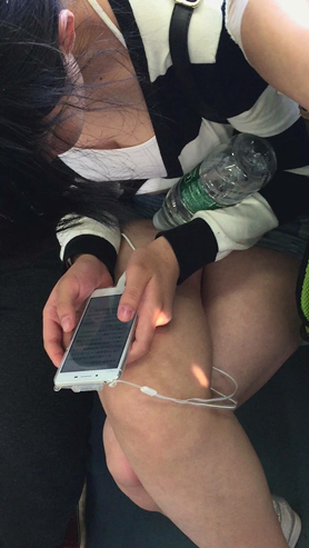 地铁上只顾着低头玩手机的女孩