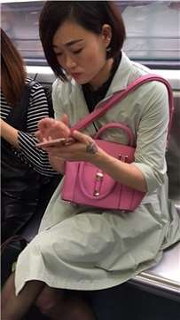 短发美女地铁上聊微信很投入