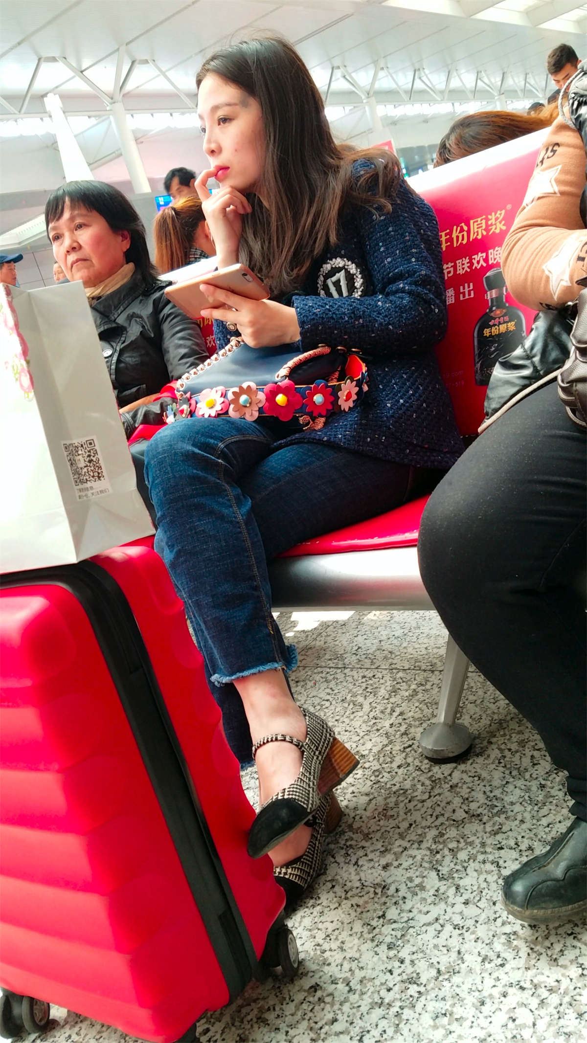 高铁站候车的蓝色紧身牛仔裤长发美少妇
