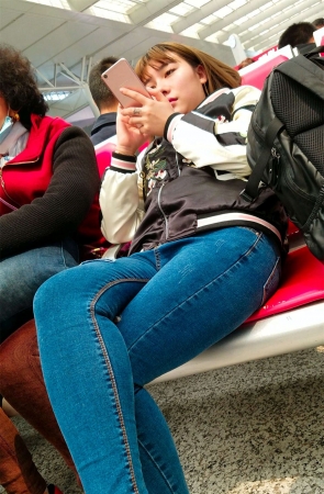 车站候车的蓝色紧身牛仔裤美眉专心玩手机
