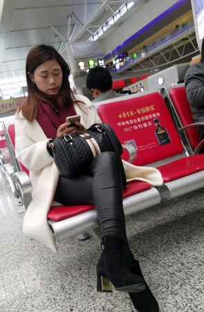 高铁站候车的黑色紧身皮裤长发少妇