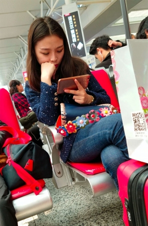 高铁站候车的蓝色紧身牛仔裤长发美少妇