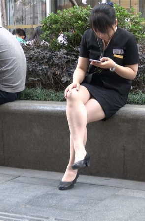 花圃边玩手机的制服街拍美女