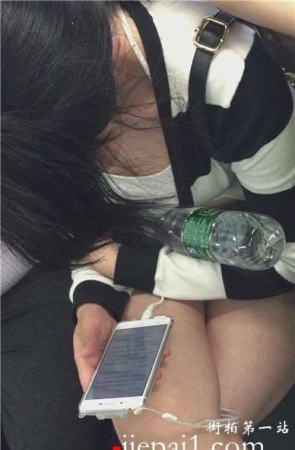 地铁上只顾着低头玩手机的女孩