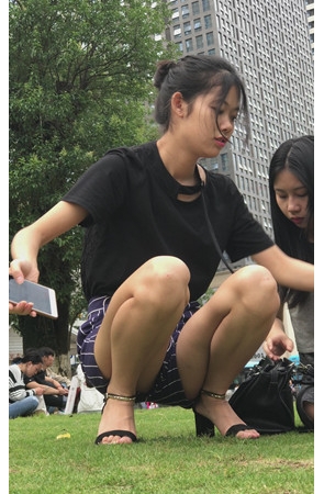 草地上玩手机的漂亮小姐姐